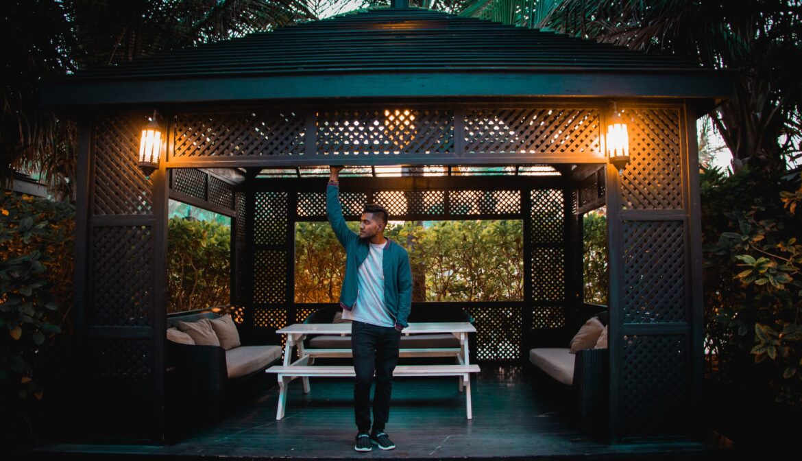 a man standing near a garden gazebo