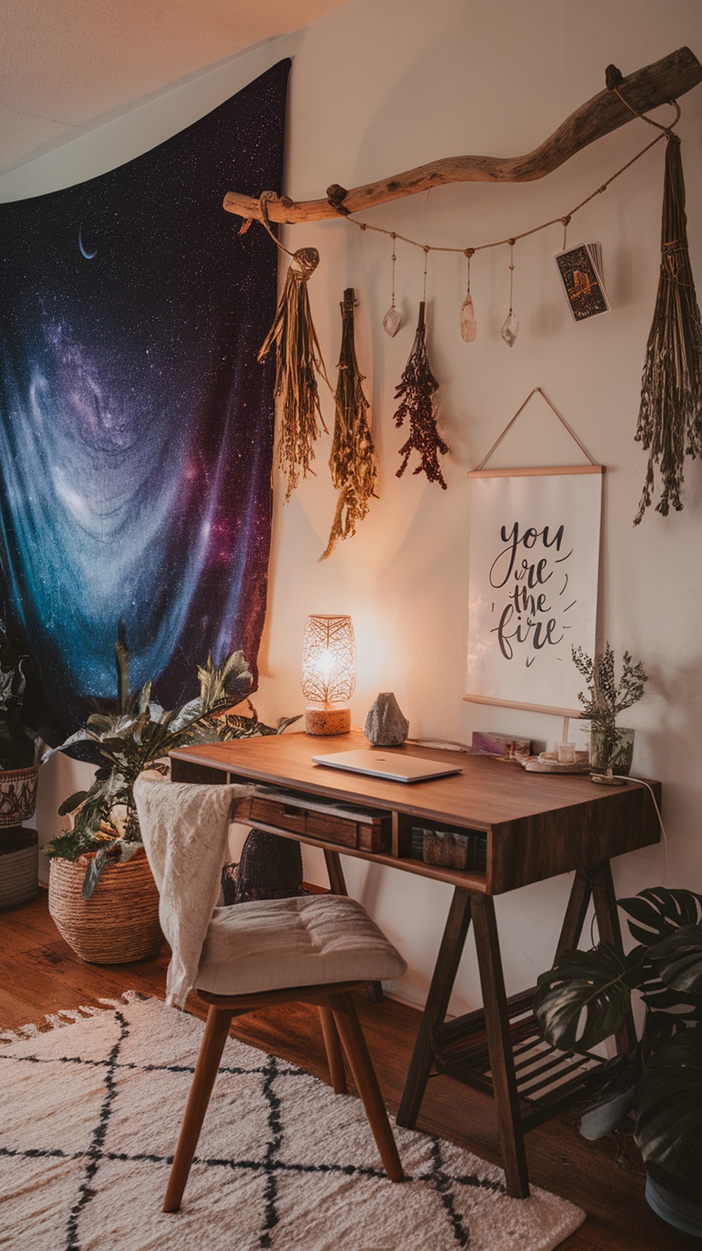 Cozy home office featuring a motivational quote framed on the wall, a galaxy tapestry, plants, and warm lighting.
