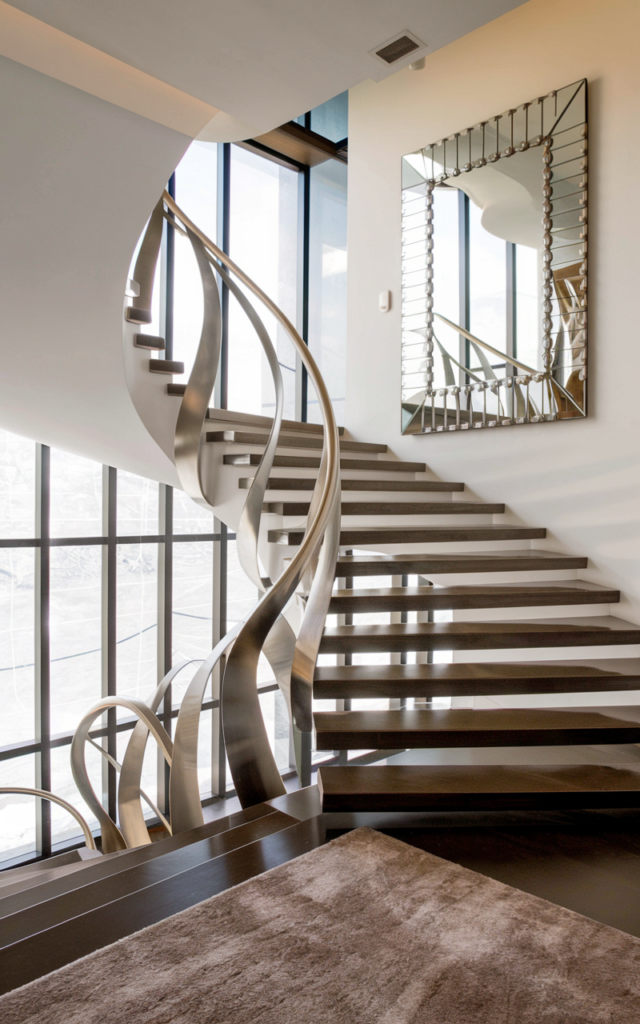 An elegant and natural-looking realistic photograph of a staircase with a sculptural curved metal handrail designed like flowing ribbons beside sleek modern stairs forming a striking design feature decorated in modern luxury home decor style with natural lighting