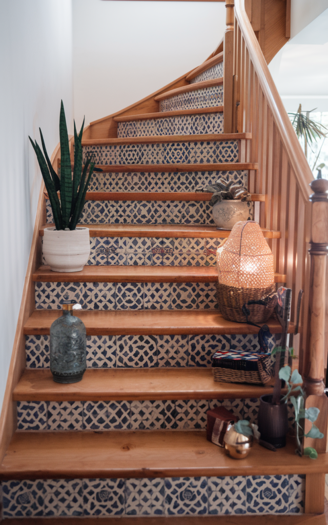 An elegant and natural-looking realistic photograph of an oak staircase featuring patterned Moroccan-inspired tiles applied to the risers adding color and personality against natural wood treads decorated in bohemian style with natural lighting