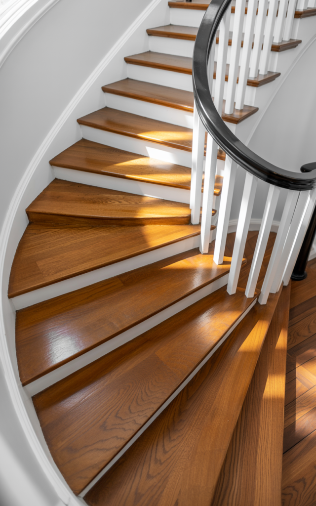 An elegant and natural-looking realistic photograph of a renovated staircase with freshly installed hardwood treads replacing old carpet, subtle satin finish and clean white risers decorated in modern classic style with natural lighting