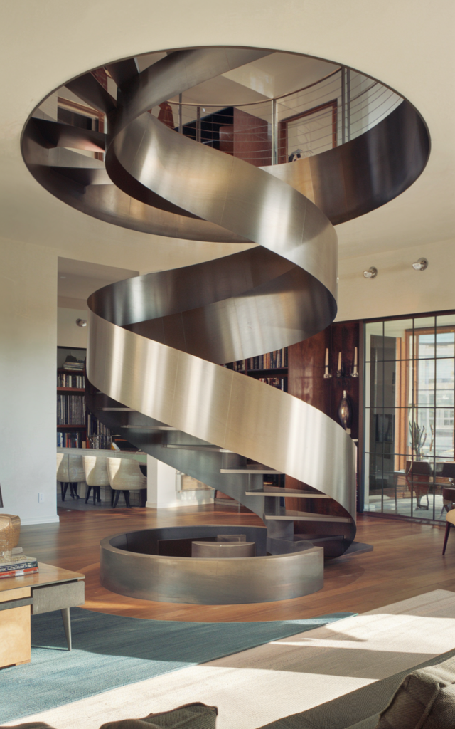 An elegant and natural-looking realistic photograph of a sculptural circular staircase made from thick curved steel plates spiraling upward like a ribbon centerpiece in a modern loft living room decorated in contemporary architectural interior style with natural lighting