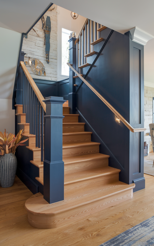 An elegant and natural-looking realistic photograph of an oak staircase with natural treads and a bold deep navy painted handrail creating a custom accent detail decorated in contemporary transitional style with natural lighting
