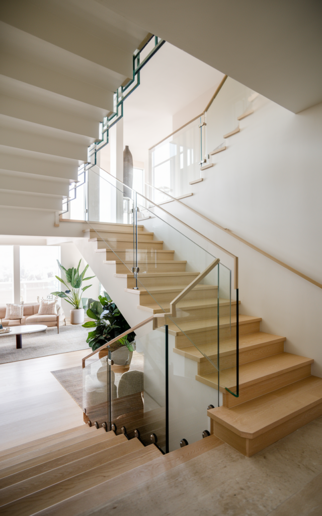 An elegant and natural-looking realistic photograph of a staircase with frameless low-iron glass panel railings replacing traditional balusters, clean lines and open layout allowing light to flow freely decorated in minimalist modern style with natural lighting