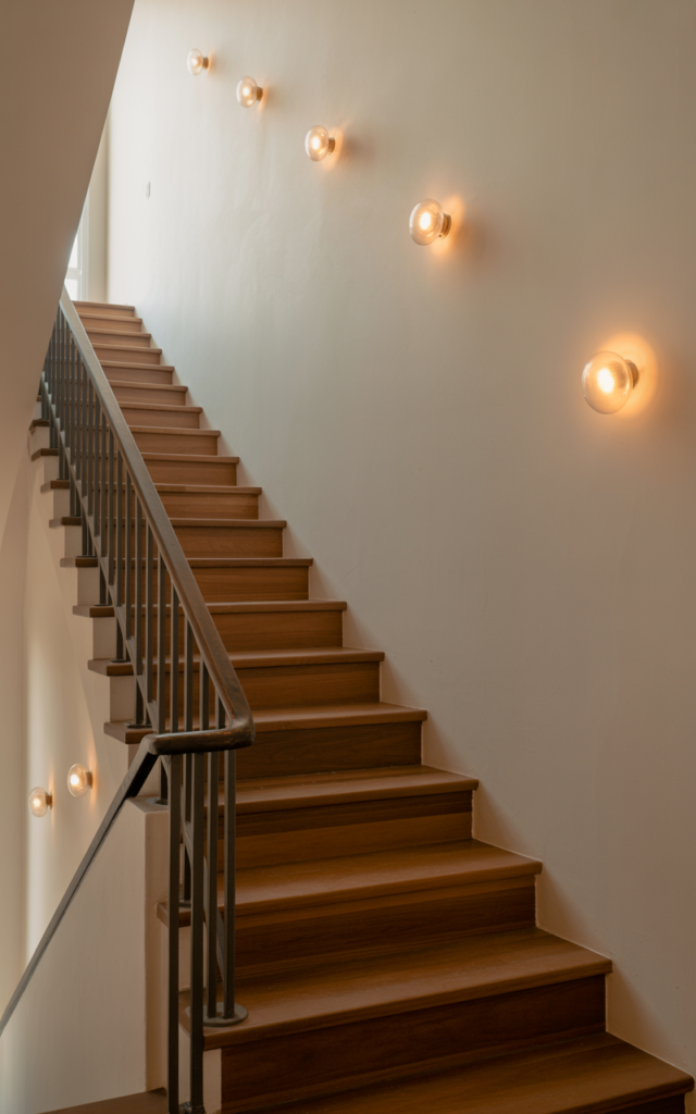 Mount wall sconces along the staircase wall.